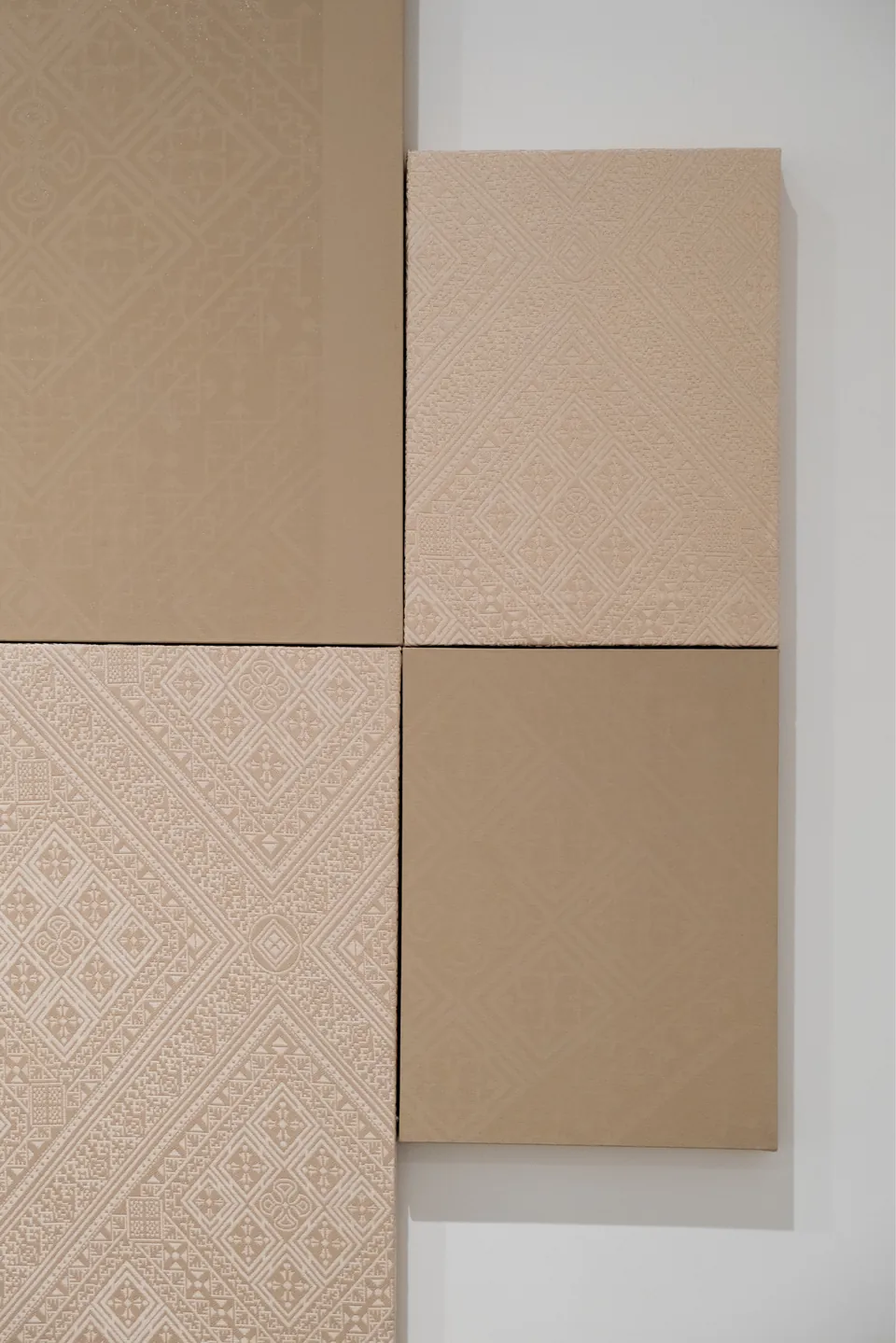 Détail : panneaux de tissu Tarz aux motifs géométriques en relief, juxtaposés à des toiles de coton brut monochromes.